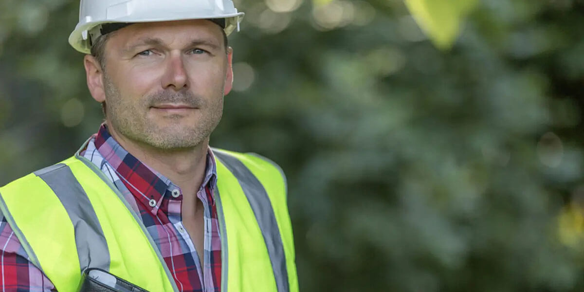 GAF master elite roofing contractor stands with clipboard in hand smiling at camera.
